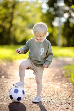 Küçük çocuk güneşli yaz gününde bir futbol oyunu oynarken eğleniyor