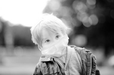 Little boy wearing medical face mask as protection against infectious diseases clipart