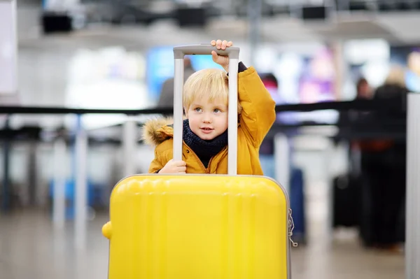 フライトの前に空港で大きな黄色のスーツケースでかわいい男の子 — ストック写真