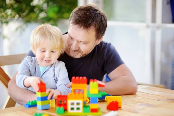 Kleiner Junge mit seinem Vater spielt zu Hause mit bunten Plastikklötzen — Stockfoto