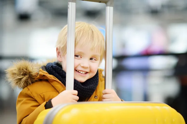Lindo niño feliz con gran maleta amarilla en el aeropuerto internacional antes del vuelo —  Fotos de Stock