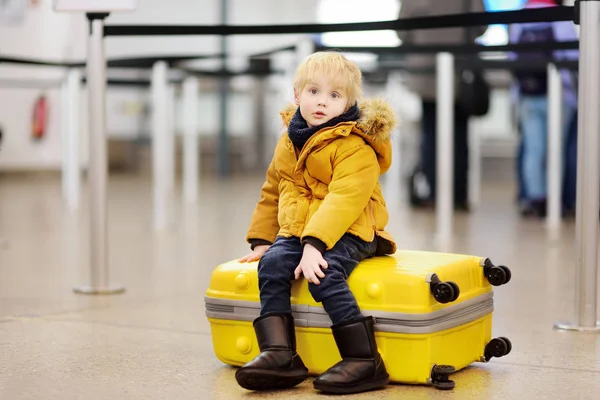 Menino bonito com grande mala amarela no aeroporto internacional antes do voo — Fotografia de Stock