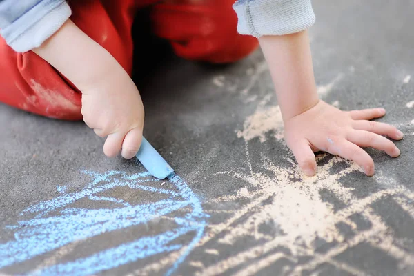 Closeup photo of little kid boy drawing with colored chalk on asphalt. — Stock Photo, Image