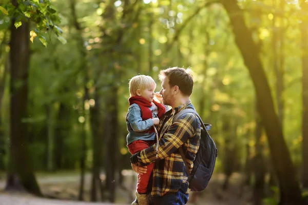 Far och hans lille son under vandring verksamhet i skogen vid solnedgången — Stockfoto