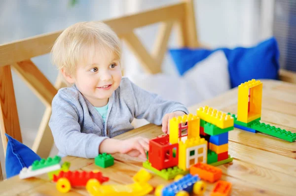 Мальчик играет с красочными пластиковыми блоками в детском саду или дома — стоковое фото