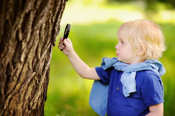 Enfant charmant explorant la nature avec une loupe — Photo