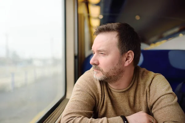 Muž středního věku při pohledu z okna vlaku — Stock fotografie