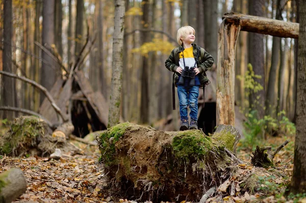 Niño explorador con binoculares durante el senderismo en el bosque de otoño. Niño está mirando a través de un prismáticos . —  Fotos de Stock