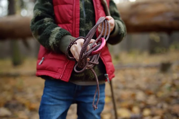 Malý skaut během turistiky v podzimním lese. Dítě drží lano s karabinou.. — Stock fotografie