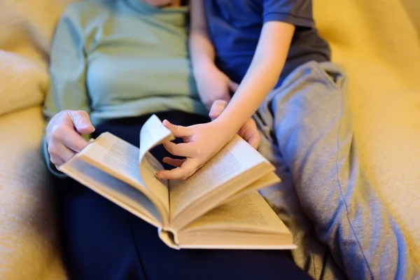 Grand-mère âgée et petit-enfant lisant un livre à la maison. Grand-mère et petit-fils . — Photo