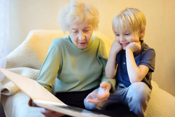 Abuela anciana y nieto pequeño buscando álbum de fotos familiares. Abuela y nieto . —  Fotos de Stock