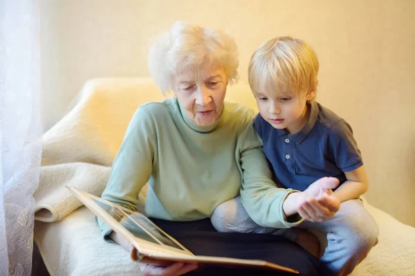 Oudere grootmoeder en kleinkind op zoek familie foto album. Oma en kleinzoon. — Stockfoto