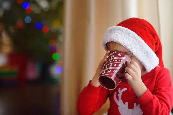 Petit garçon buvant du chocolat chaud dans un salon confortable décoré. Joyeux enfant à Noël. Activité pour les enfants en vacances d'hiver — Photo