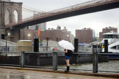 Brooklyn Köprüsü yakınlarındaki New York 'ta yağmurlu bir günde şemsiyenin altında genç bir kadın.