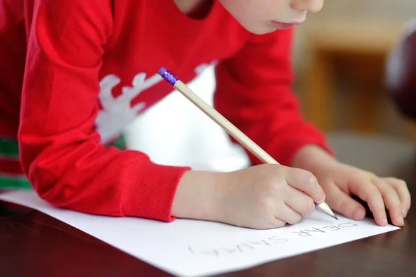 Мальчик пишет письмо Санте. Ребенок мечтает о даре, который он может получить . — стоковое фото