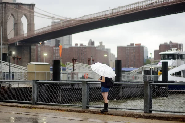 Young woman under the umbrella on a rainy day in New York city near Brooklyn bridge — Stock Photo, Image