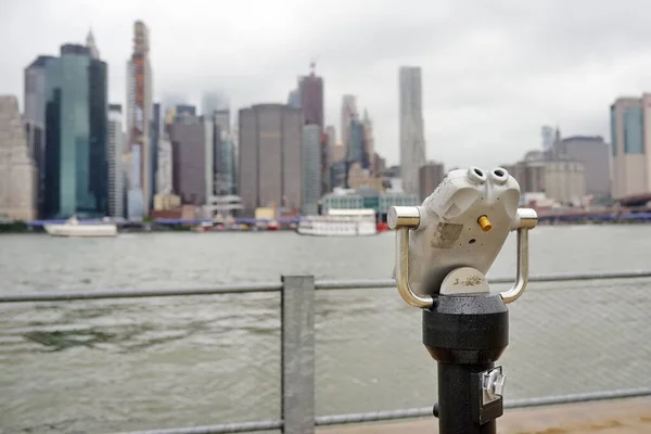 Binoculars looking to the Manhattan skyline over East River in rainy day. — Stock Photo, Image