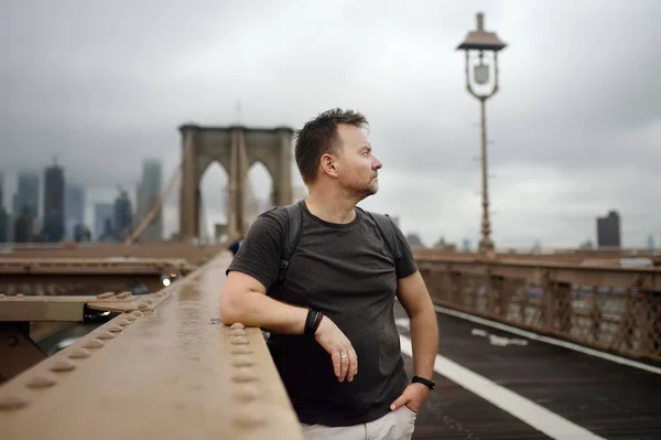 Hombre en un famoso puente de Brooklyn en el lluvioso día de verano . — Foto de Stock