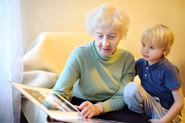 Oudere grootmoeder en kleinkind op zoek familie foto album. Oma en kleinzoon. — Stockfoto