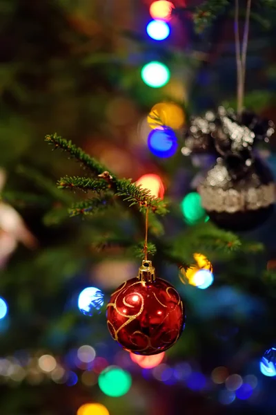 Part of christmas decorating house interior. Branch of xmas fir tree Illuminated garland. Xmas bauble toy closeup. — Stock Photo, Image