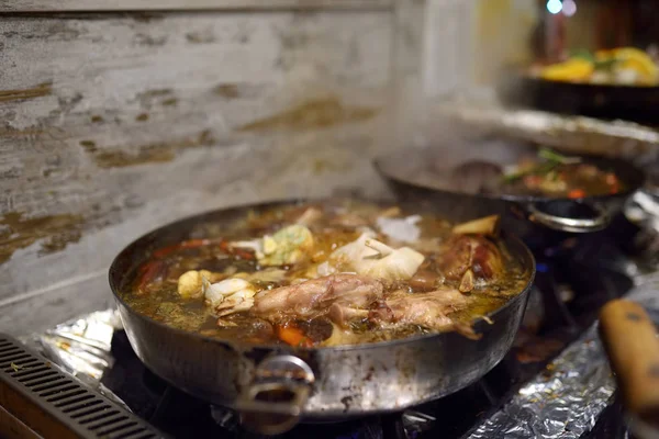 Traditioneel eten op de kerstmarkt - gestoofd varkensvlees. Deze cursus is koken van varkensvlees, ui, knoflook en wortelen in een koekenpan. — Stockfoto