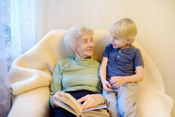 Avó idosa e netinha lendo um livro em casa. Avó e neto . — Fotografia de Stock