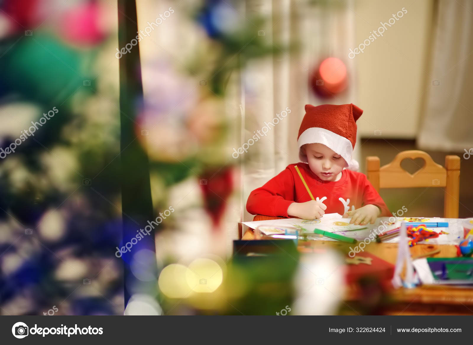 Niño vistiendo un disfraz de Santa está dibujando cerca de un árbol de ...