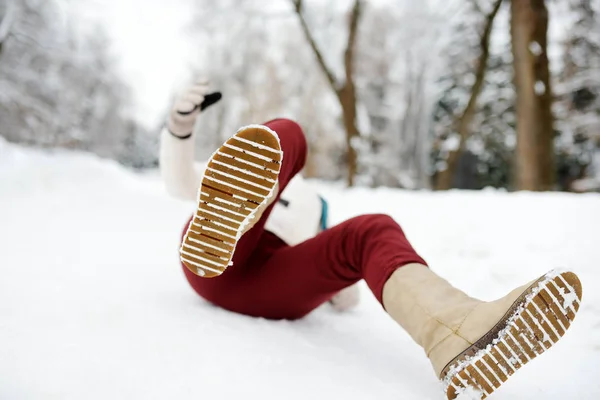 Shot van persoon tijdens het vallen in besneeuwde winterpark. Vrouw gleed uit op het ijzige pad, viel en liegt.. — Stockfoto