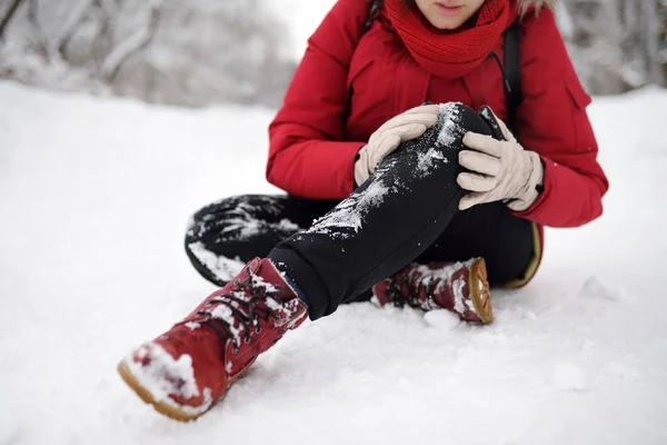 Skjuten av person under faller i snöig vinterpark. Kvinna halka på den isiga vägen, föll, skada knä och sitter i snön. — Stockfoto