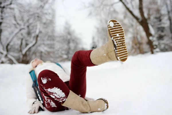 Shot of person during falling in snowy winter park. Woman slip on the icy path, fell and lies. — Stock Photo, Image