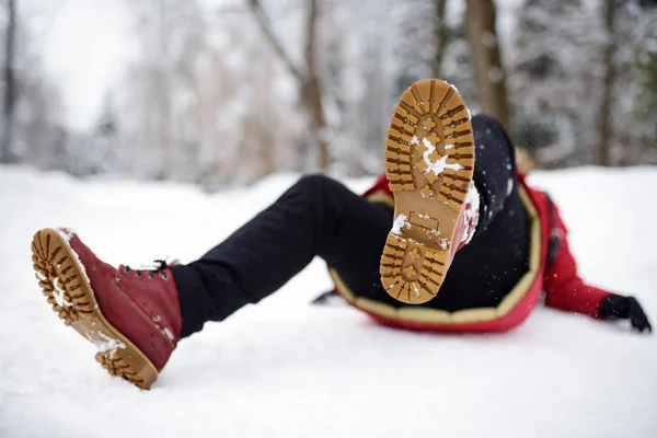 Skjuten av person under faller i snöig vinterpark. Kvinna halka på den isiga vägen, föll och ligger. — Stockfoto