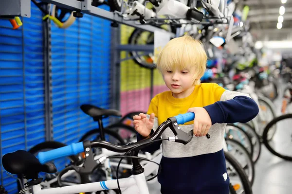 Kleine jongen kiezen fiets in de sportwinkel. — Stockfoto