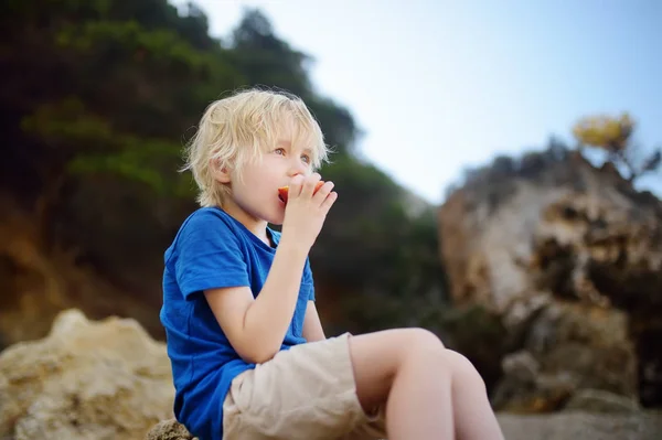 Little boy is eating peach during walking. Nature lover. — Stock Photo, Image