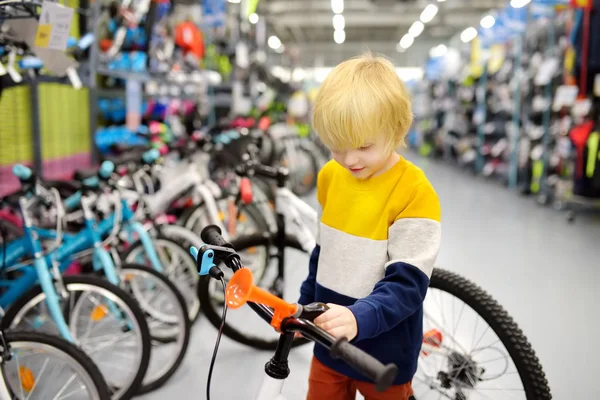 Kleine jongen kiezen fiets in de sportwinkel. — Stockfoto