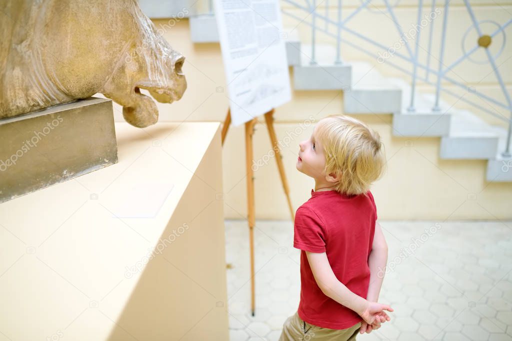 Little boy looking at sculpture of horse's head.