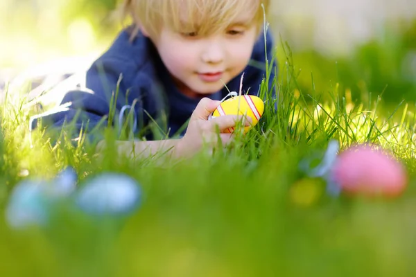 Kleiner Junge auf Ostereiersuche im Frühlingsgarten am Ostertag. Bunte Eier im Fokus. — Stockfoto