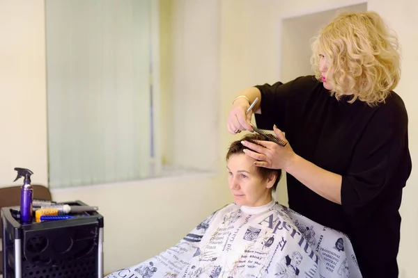 美容室で中年女性のための髪型を作る美容師。女性のための短い散髪. — ストック写真