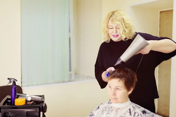 Friseur macht Frisur für Frau mittleren Alters im Schönheitssalon. Kurzhaarschnitt für Frauen. — Stockfoto