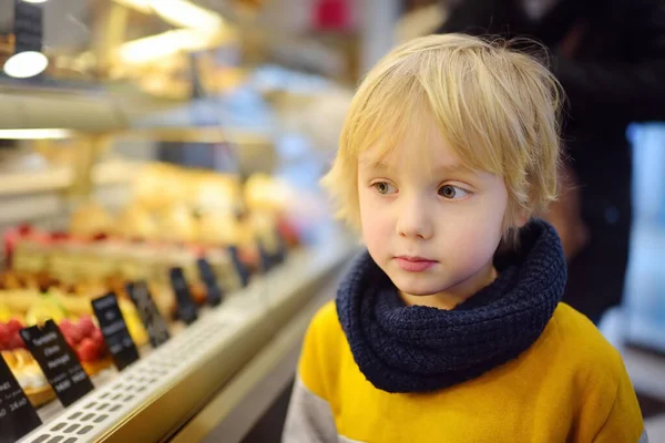 小さな男の子はカフェやスーパーマーケットでショーケースにケーキや他のお菓子を賞賛しています 子供の食事 不健康な食べ物 不寛容乳糖またはグルテン — ストック写真