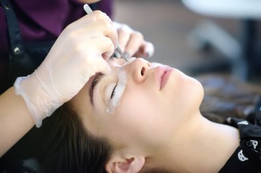 Kirpik kaplama prosedürleri yapan bir güzellik uzmanı. Modern kirpik bakım prosedürleri - kirpikleri boyama, kıvırma, kaplama ve uzatma. Profesyonel güzellik salonu..