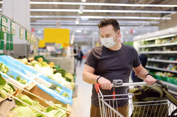 Koronavirüs salgını sırasında süpermarkette tek kullanımlık maske takan bir adam. Salgın sırasında tedbirlerin korunması ve önlenmesi.
