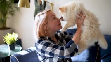 Genç bir kadın 2 aylık Pomeranya tükürük köpeğiyle oynuyor. Şirin tüylü küçük köpek. Evcil hayvanıyla sevecen kadın sahibi.