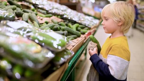 Söt Liten Pojke Välja Färska Ekologiska Gurkor Och Sätta Mesh — Stockvideo