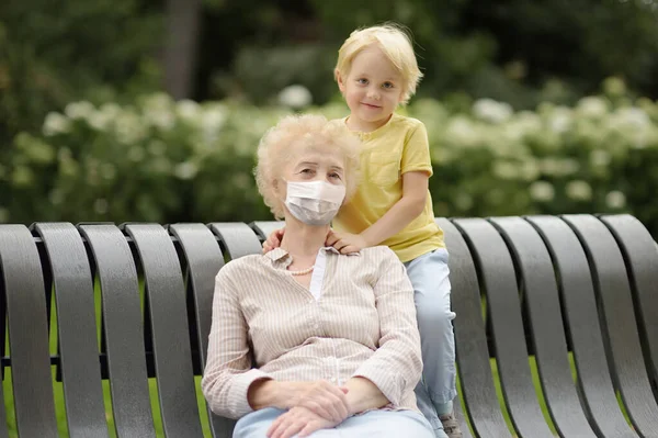 老太太和她的小孙子一起在公园里散步 在大肠病毒爆发期间 公共场所的安全 病毒感染的流行D — 图库照片