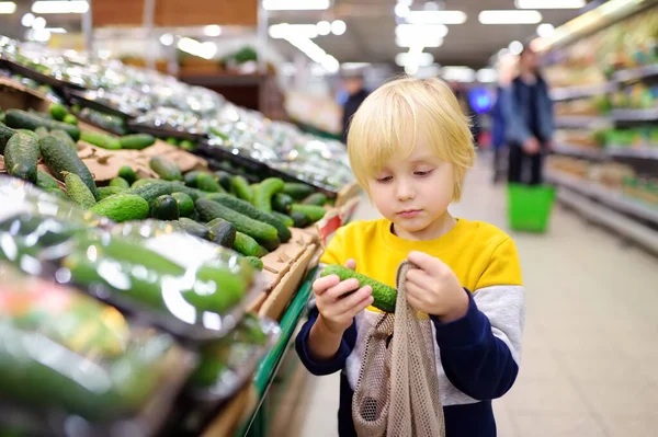 Kleine Jongen Kiezen Biologische Komkommers Zet Mesh Boodschappentas Voedselwinkel Supermarkt — Stockfoto