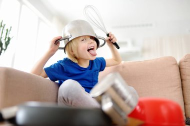 Yaramaz anaokulu çocuğu evde karantina sırasında mutfak aletleri ve çatal bıçak kullanarak müzik çalıyor. Çocukluktan komik davul kısmı. Evde küçük çocuklar eğleniyor..