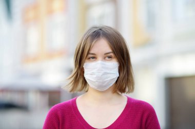 Şehir caddesinde koruyucu maske takan genç bir kadın. COVID-19 salgını sırasında güvenlik. Koronavirüs salgını..