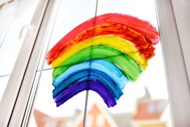 Koronavirüs karantinadayken ev penceresine gökkuşağı çizimi yapmak. Gökkuşağı işareti umudun sembolüdür, her şeyin yoluna gireceği anlamına gelir. Coronavirüs 'ü kilitlemek için evde tecritte kalın..