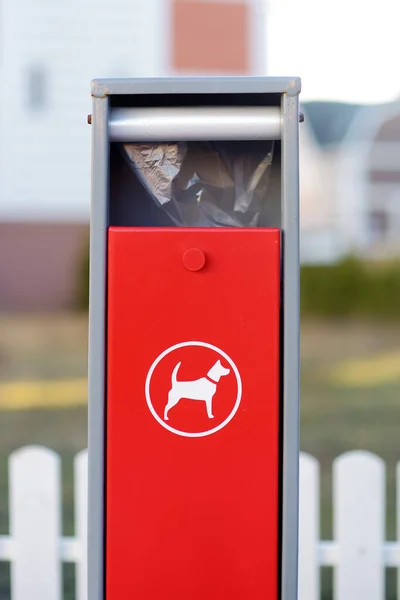 Red dispenser with bag for dog excrement sign on street small town. Pet waste transmits disease. Clean up after your pet.