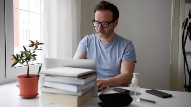 コロナウイルスの発生の間 自宅のラップトップコンピュータでオンラインで働いている男 隔離中は家にいて リモートトレーニング 新しい職業 — ストック動画